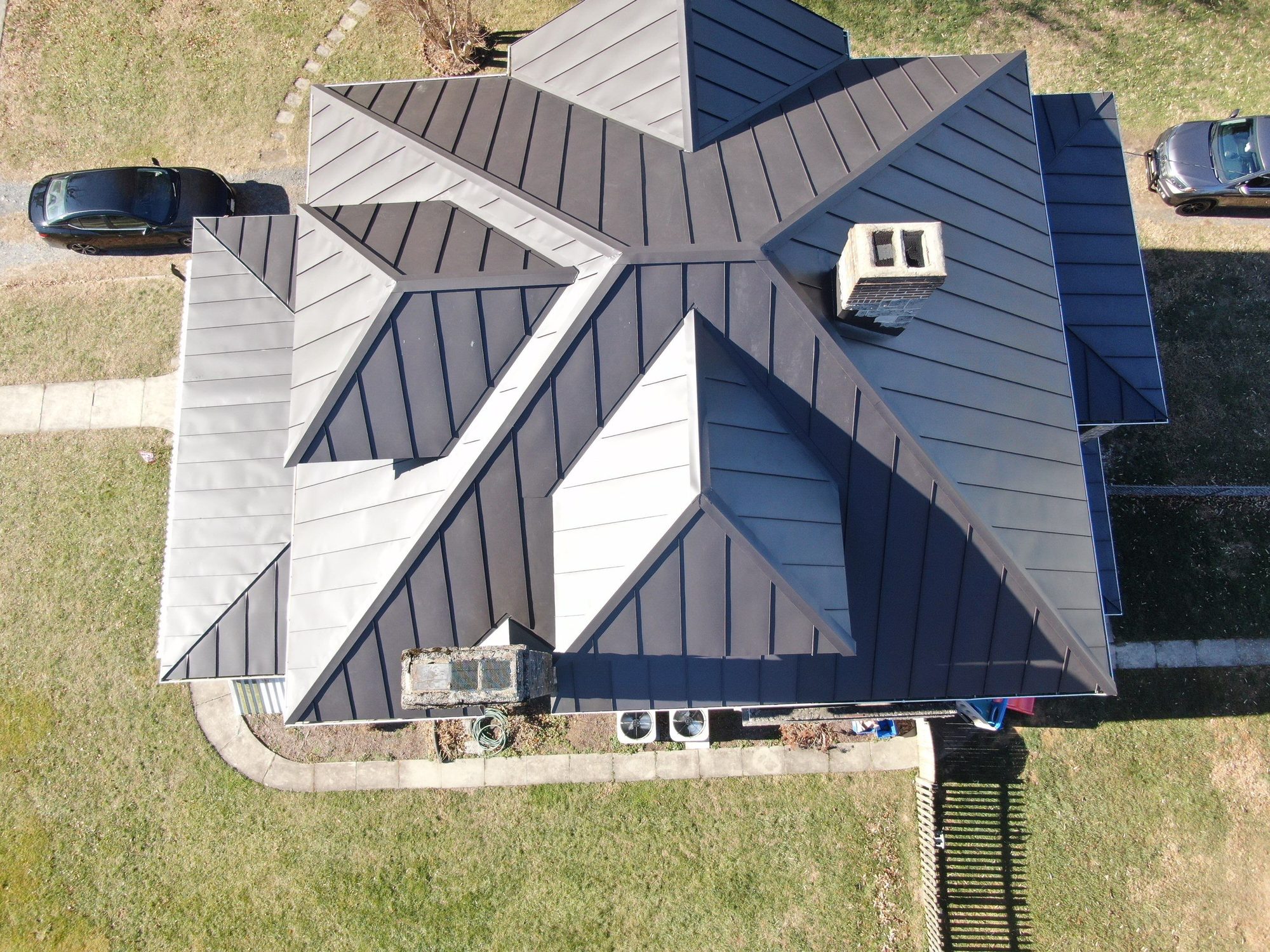 Overhead drone view of a dark standing-seam hip roof