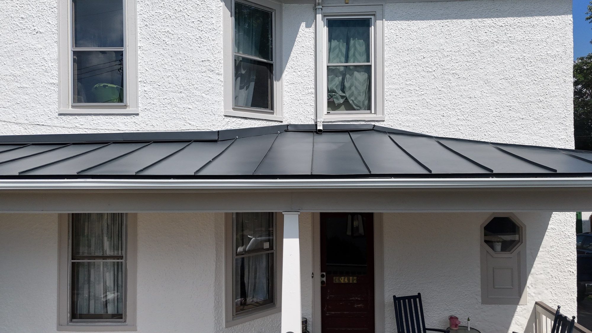 Standing-seam porch roof on a white house