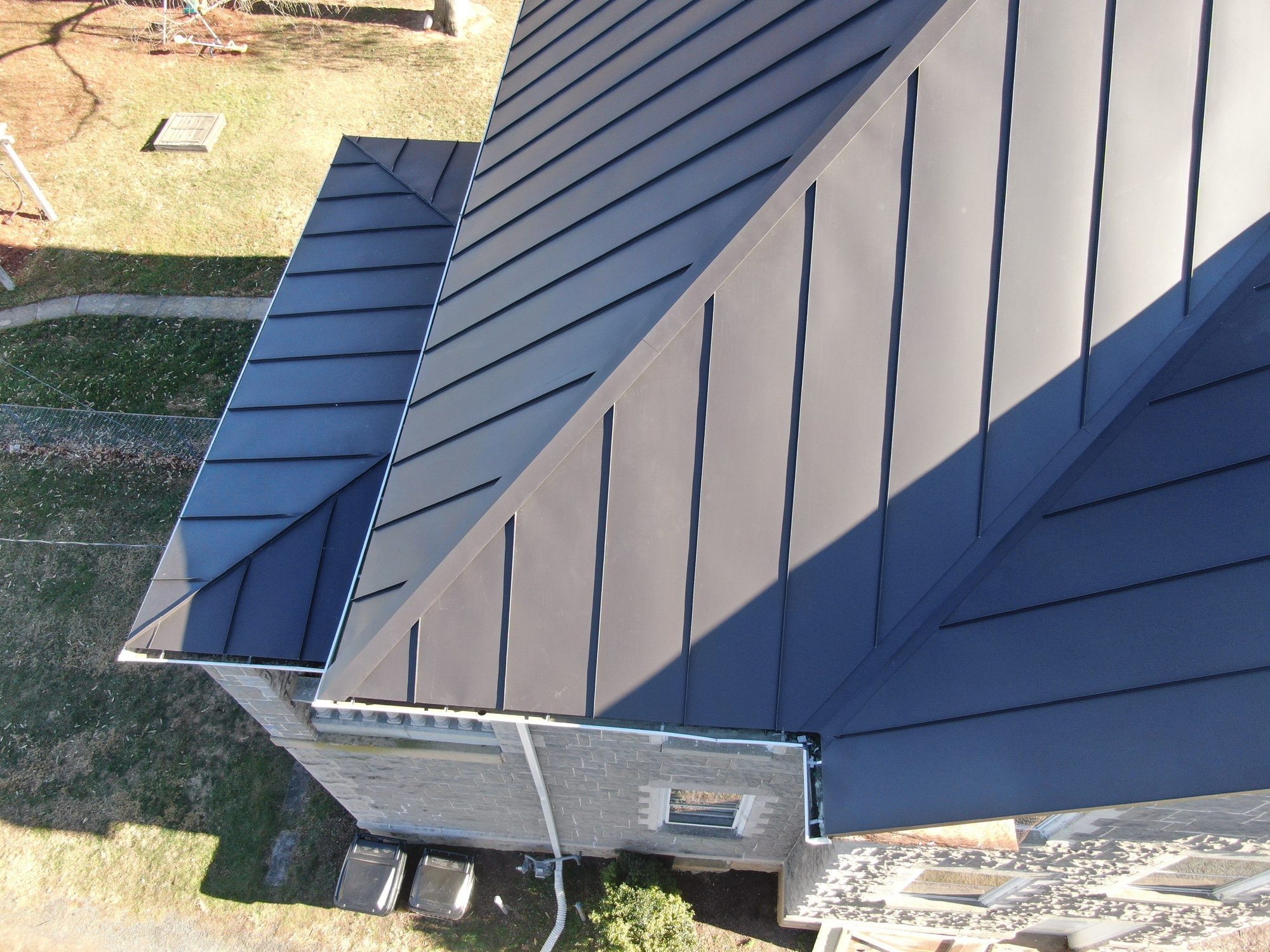 Dark standing-seam roof on a stone house